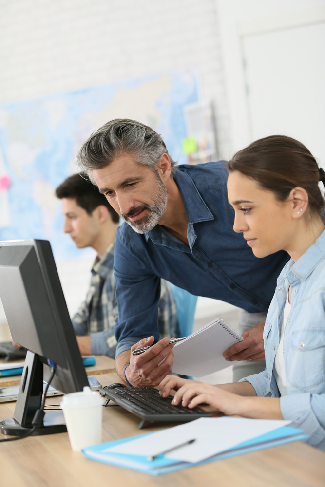 Trainer with student working on desktop computer